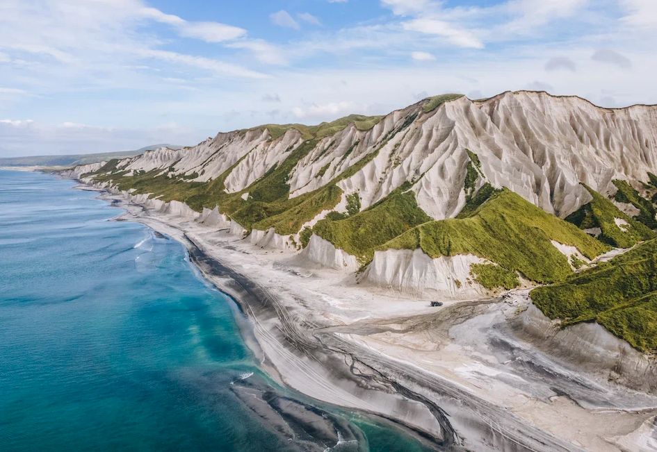 Белые скалы и пляж с черным вулканическим песком Итуруп Курилы Курильские острова